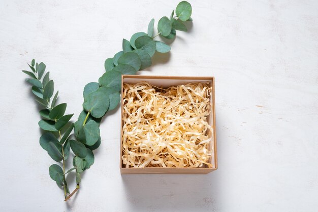 Boîte en carton marron avec remplissage décoré d'une branche verte d'eucalyptus