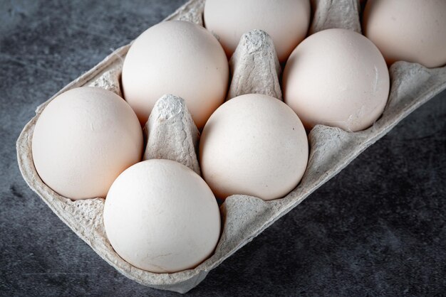 Boîte en carton avec oeufs sur table grise