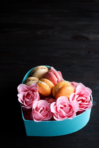 Boîte coeur bleu avec macarons et Rose sur fond en bois foncé, espace copie