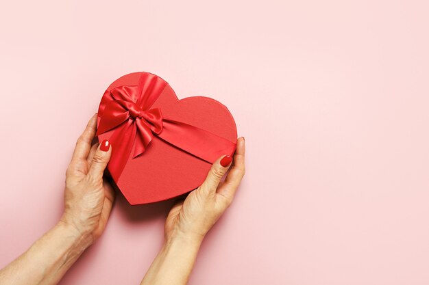 Boîte de coeur de la Saint-Valentin dans les mains de la femme sur le rose