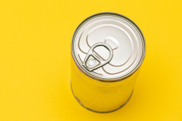 Boîte de conserve non ouverte avec bord vierge sur fond jaune