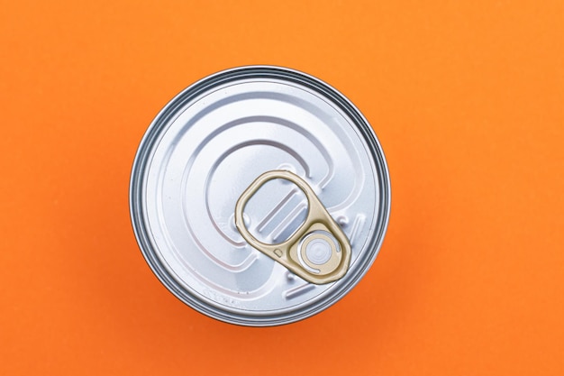 Boîte de conserve non ouverte avec bord vierge sur fond orange