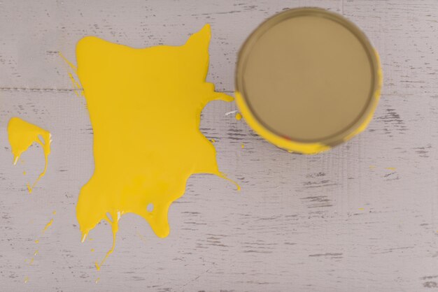 Boîte de conserve de peinture jaune avec des traits jaunes sur le plancher en bois