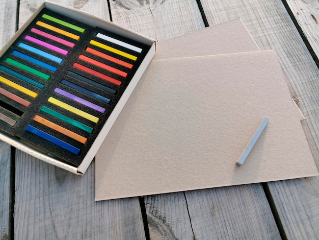 Une boîte de crayons pastel ou de peintures sur des planches en bois un arrière-plan légèrement flou avec des outils de dessin