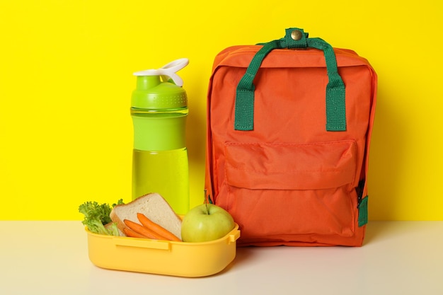 Photo une boîte à déjeuner jaune avec un sac d'école