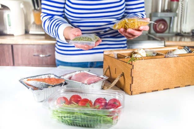 Boîte à démonter pour femme de race blanche avec livraison d'ingrédients, recettes. Concept de livraison de kit de repas. Définissez divers aliments sains avec des recettes de cuisine. Commande en ligne de livraison d'épicerie de chef de restaurant