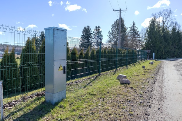 Boîte de distribution électrique métallique devant la clôture