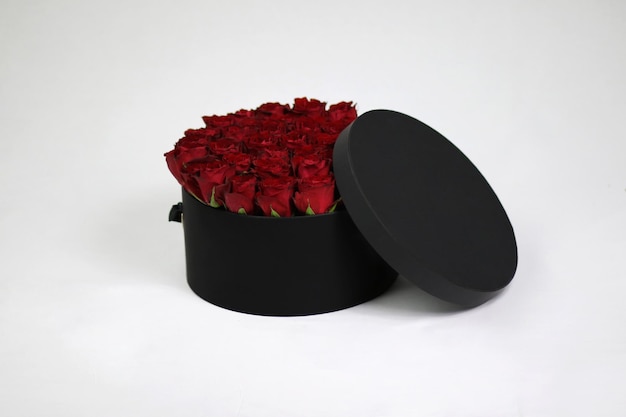 Photo boîte d'emballage de fleurs cadeau ronde noire avec des roses rouges à l'intérieur et un couvercle ouvert
