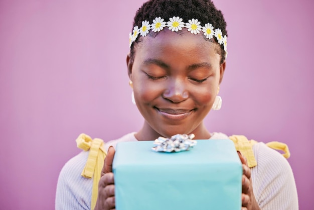 Boîte de femme africaine et cadeau avec les yeux fermés dans le mur du studio et surprise pour la célébration d'anniversaire ou le sourire Femme noire présente ou bonheur pour la beauté de la couronne de fleurs de printemps et fond de lavande