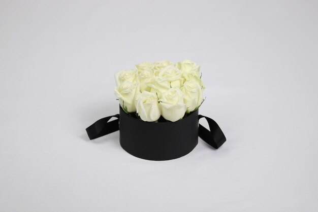 Boîte à fleurs cadeau ronde noire avec des roses blanches à l'intérieur