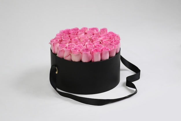 Boîte à fleurs cadeau ronde noire avec des roses roses à l'intérieur