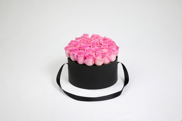 Boîte à fleurs cadeau ronde noire avec des roses roses à l'intérieur