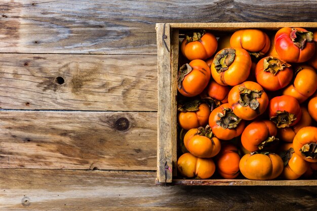 Boîte de fruits kaki kaki sur fond en bois. Espace de copie