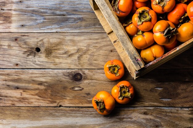 Boîte de fruits kaki kaki sur fond en bois