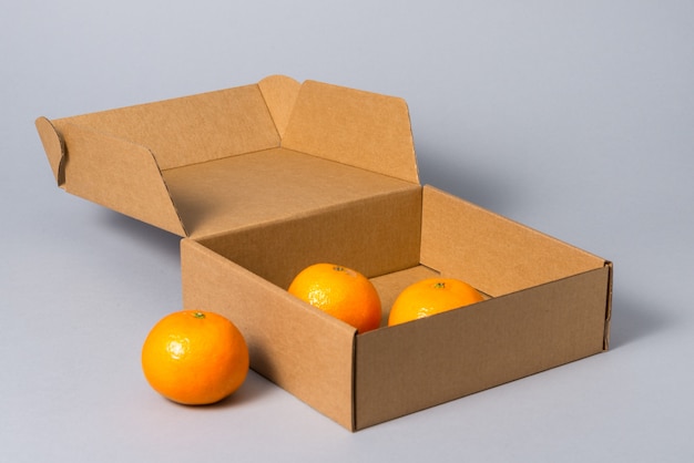 Boîte de gâteau en carton brun avec couvercle avec des fruits, sur fond gris