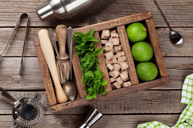 Boîte d'ingrédients pour cocktails Mojito et d'accessoires de bar sur table en bois, vue sur le dessus