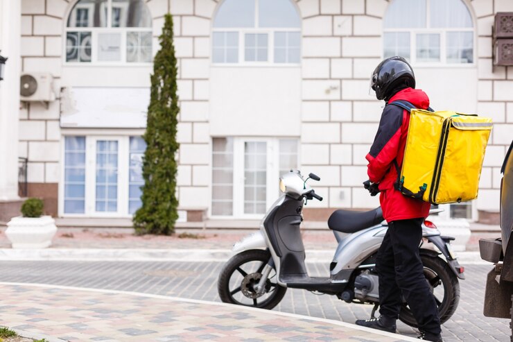 Boîte de livraison jaune sur moto avec livreur devant la maison.