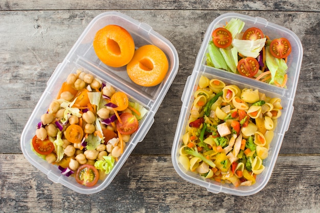 Boîte à lunch avec des aliments sains prêts à manger sur table en bois