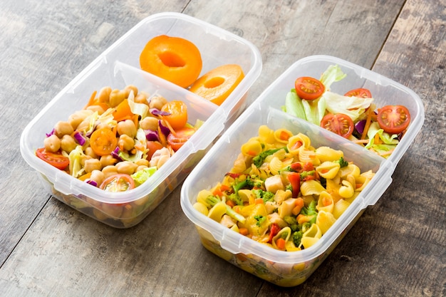 Boîte à lunch avec des aliments sains prêts à manger sur table en bois