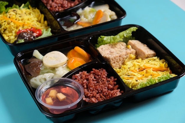 boîte à lunch de concept d'aliments sains avec riz brun, poulet râpé, soupe de légumes, tofu au tempeh. diète