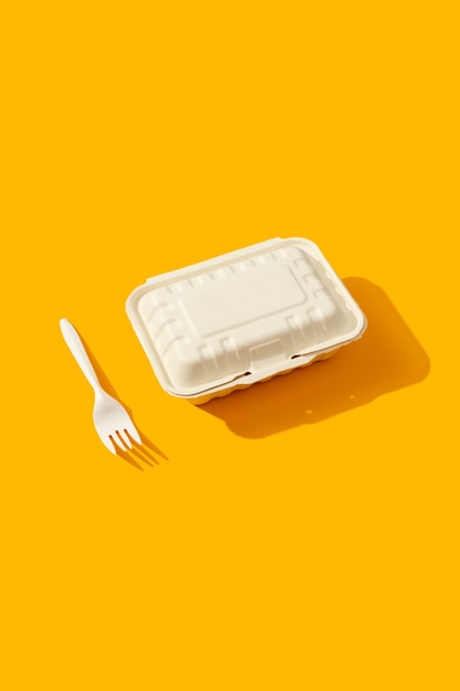 Boîte à lunch et fourchette sur table orange avec ombre portée