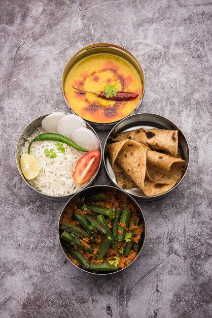 Boîte à lunch indienne végétarienne ou Tiffin en acier inoxydable pour le bureau ou le lieu de travail, comprend Dal Fry, Bhindi Masala, riz avec chapati et salade