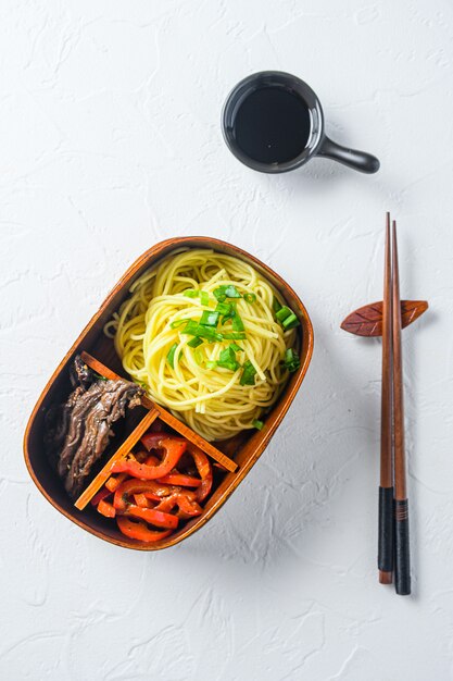 Boîte à lunch de nouilles de boeuf bento sur table blanche.