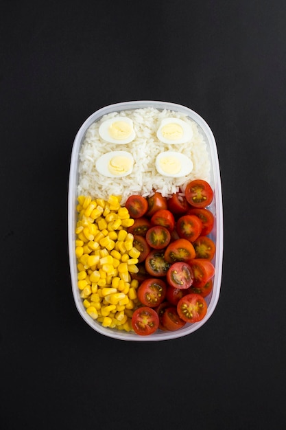 Boîte à lunch avec œufs de caille de légumes et riz blanc sur fond noir Vue de dessus Gros plan