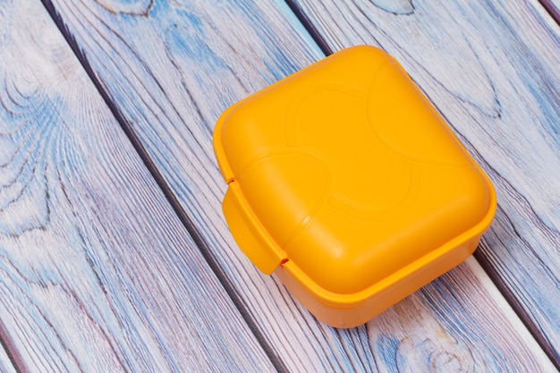 Boîte à lunch en plastique jaune sur la surface en bois