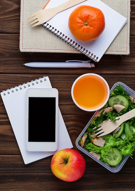 Boîte à lunch avec salade, carnet et téléphone