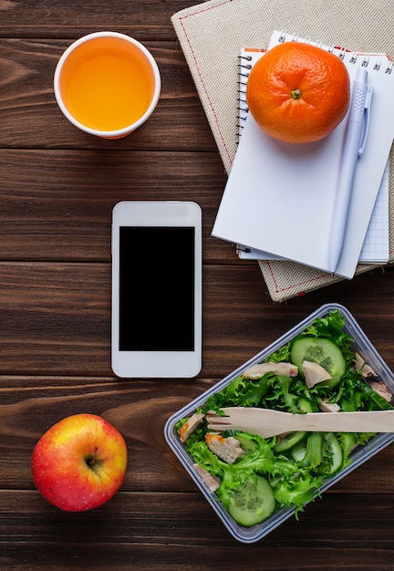 Boîte à lunch avec salade, carnet et téléphone