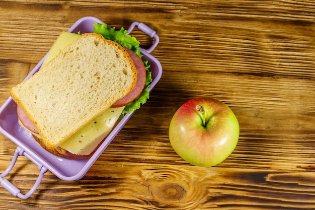 Boîte à lunch avec sandwichs et pomme sur une table en bois Vue de dessus