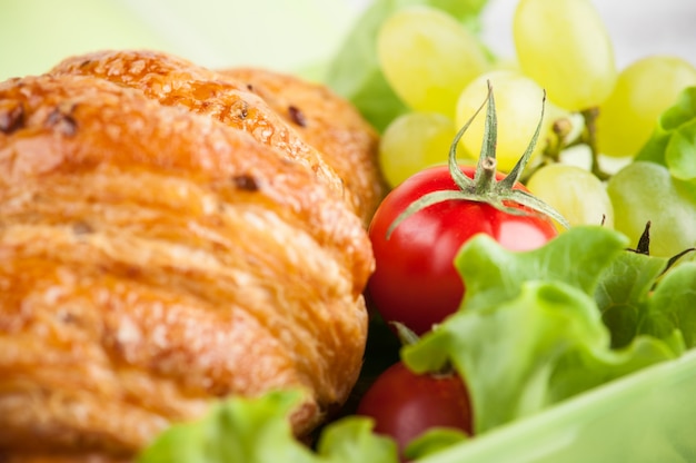 Boîte à lunch verte avec croissant, salade