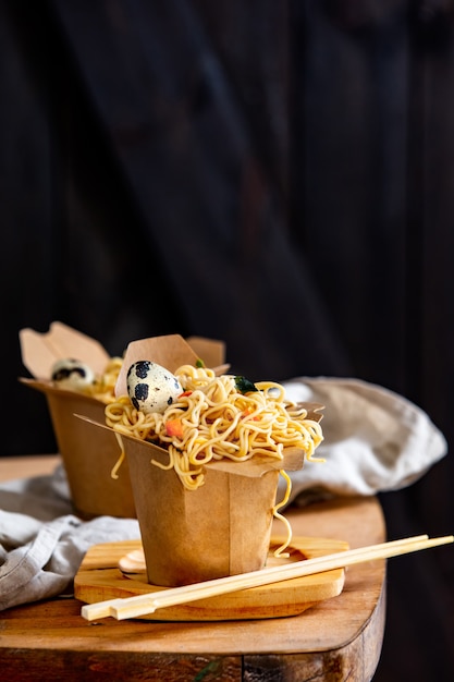 Boîte avec nouilles et oeuf de caille sur une table