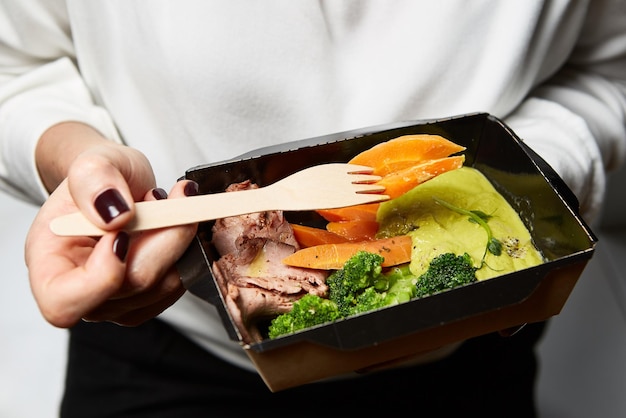 Photo une boîte de nourriture entre les mains d'un serveur pendant la restauration