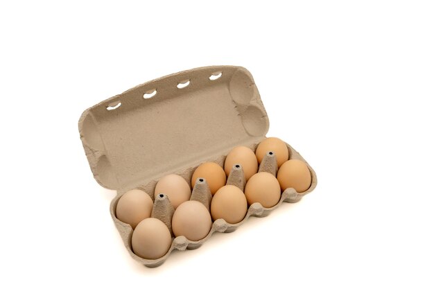 Boîte à œufs en carton avec dix œufs de poule isolés sur fond blanc avec espace de copie