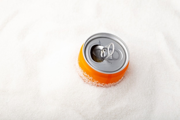 Boîte orange de boisson gazeuse sucrée et tas de sucre Excès de sucre dans les boissons gazeuses Soda