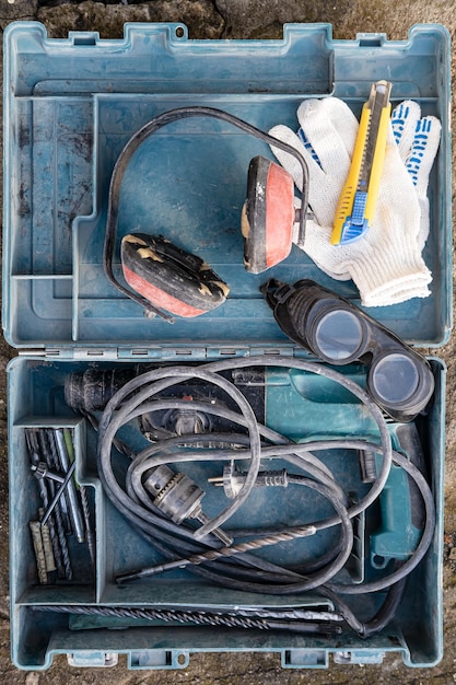 Boîte à outils ouverte contenant un casque de travail insonorisé et une perceuse à percussion électrique