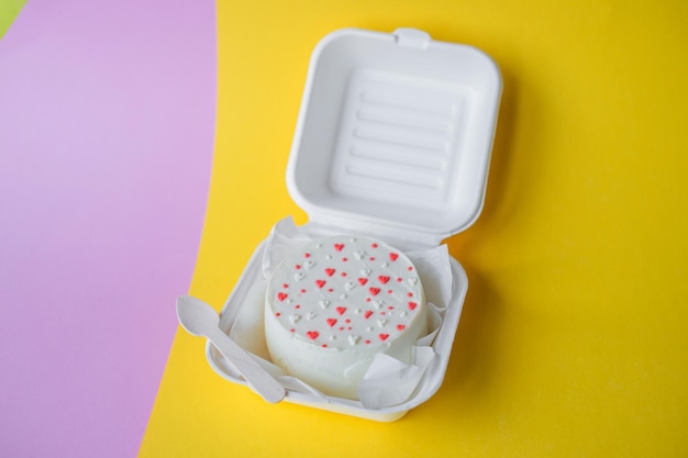 Une boîte ouverte avec un gâteau bento de la Saint-Valentin avec des coeurs se dresse sur un fond jaune