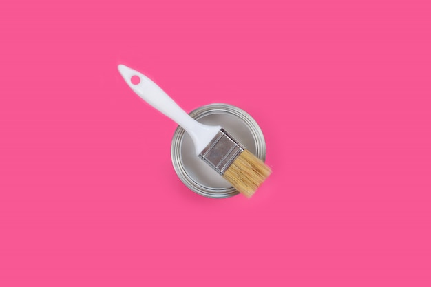 Boîte ouverte avec peinture blanche et pinceau sur fond rose,
