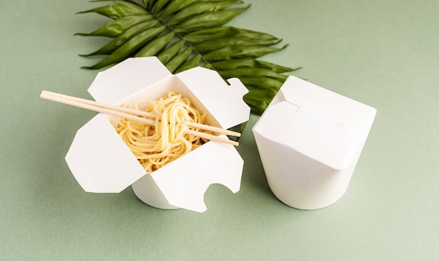 Boîte de papier WOK ouvert avec des nouilles et des baguettes, maquette vue de dessus de conception à plat sur fond vert