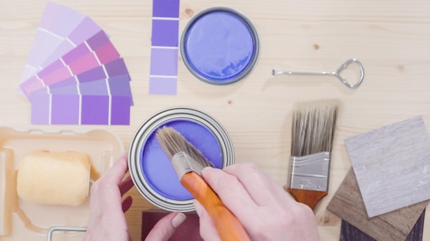 Boîte de peinture en métal avec de la peinture violette et d'autres outils de peinture pour un projet de rénovation domiciliaire.