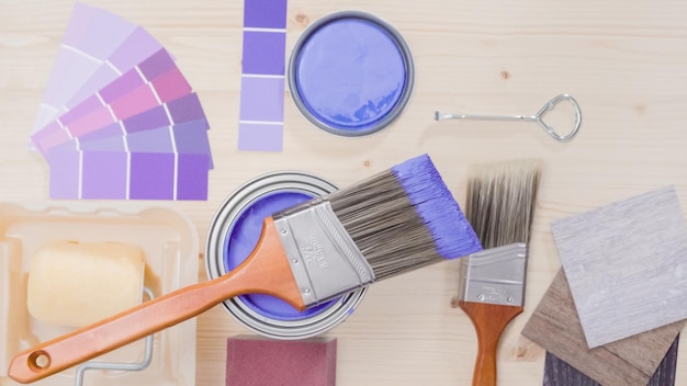 Boîte de peinture en métal avec de la peinture violette et d'autres outils de peinture pour un projet de rénovation domiciliaire.