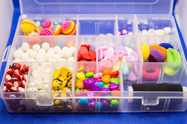 Photo boîte en plastique avec de petits accessoires pour la couture dans des cellules séparées fond bleu