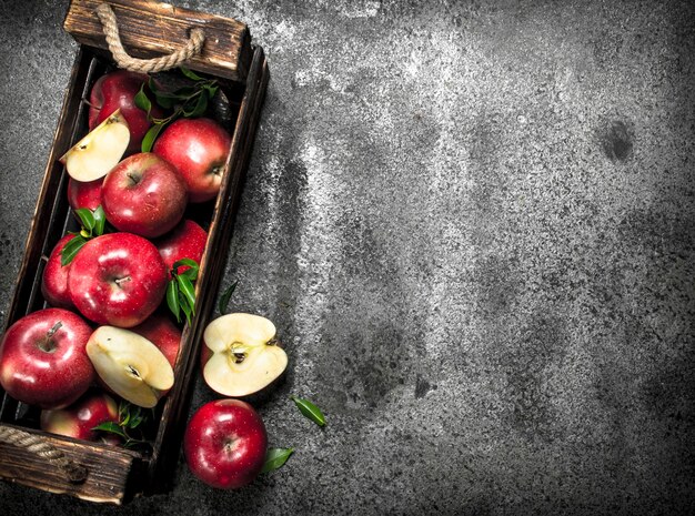 Boîte avec pommes rouges mûres. sur un fond rustique.