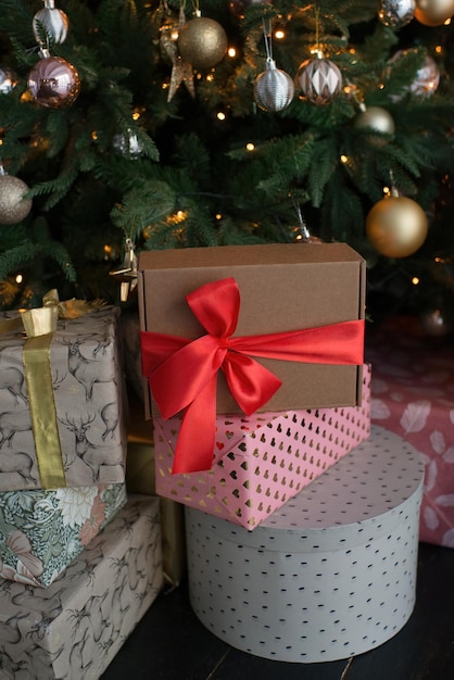 Une boîte avec un ruban rouge, un cadeau se trouve sous le sapin de Noël