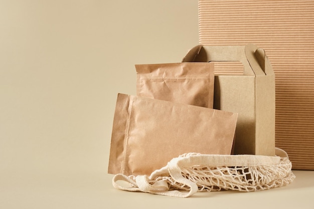 Boîte et sacs en papier zippés dans un sac en filet pour faire du shopping fond beige vue de dessus emballage de maquette pour produits emballages pour livraison matériaux naturels respectueux de l'environnement neutre en CO2