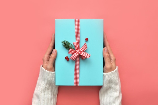 Une boîte de vacances bleue entre les mains d'une femme. La surprise du nouvel an