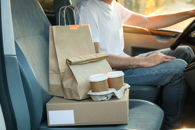 Boîte vide, tasses à café, paquets de papier et courrier en voiture. Livraison