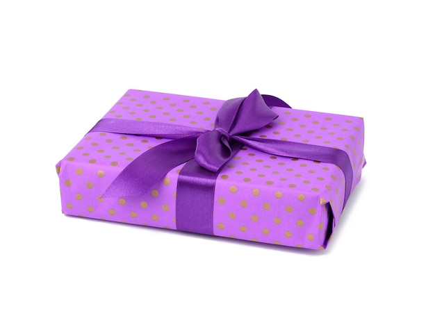 Photo boîte violette enveloppée dans du papier à pois bleu et attachée avec un ruban de soie sur fond blanc, célébration